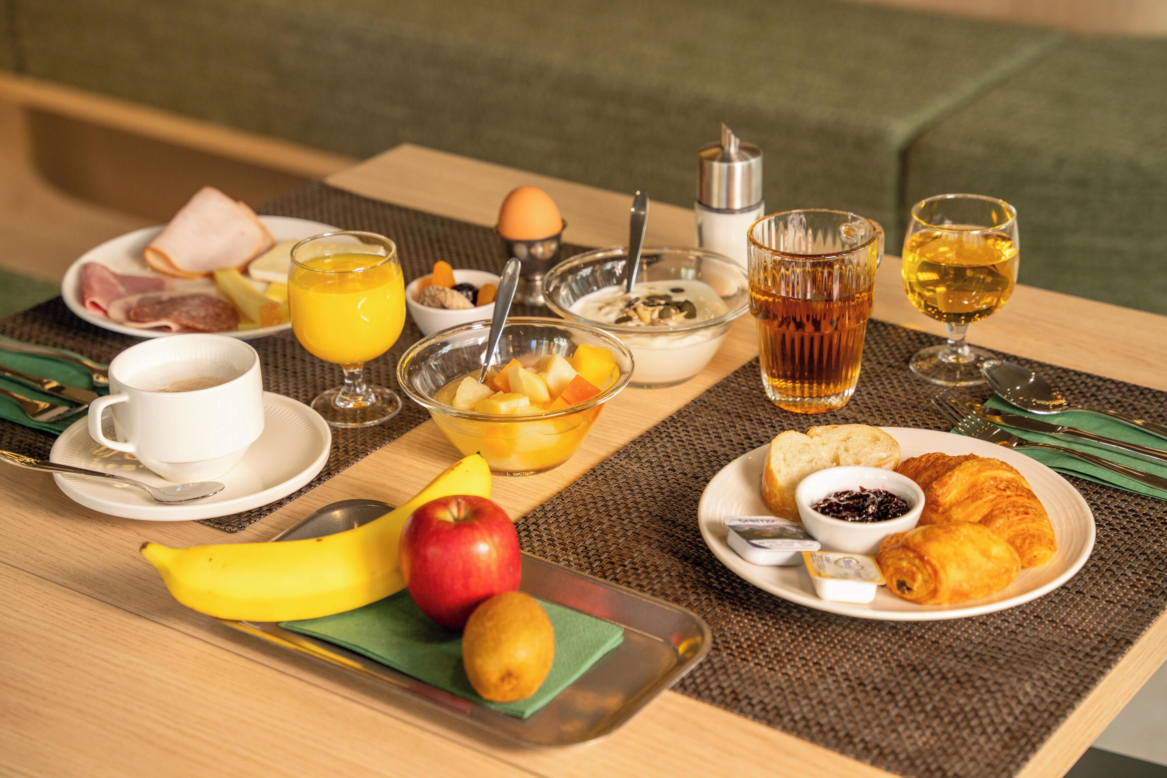 Un desayuno con una variedad de alimentos, como frutas, pasteles y bebidas, colocados sobre una mesa.