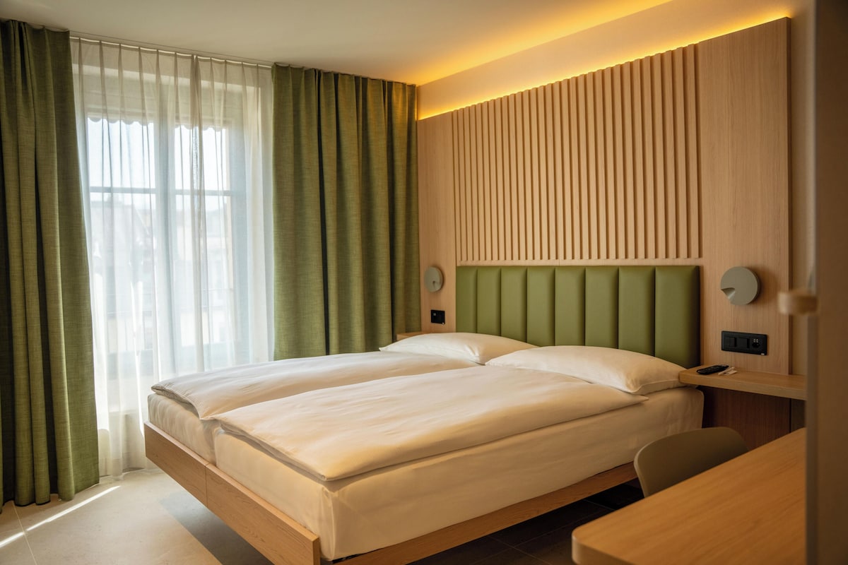 Un lit double avec une tête de lit en bois, une table de chevet et une chaise.