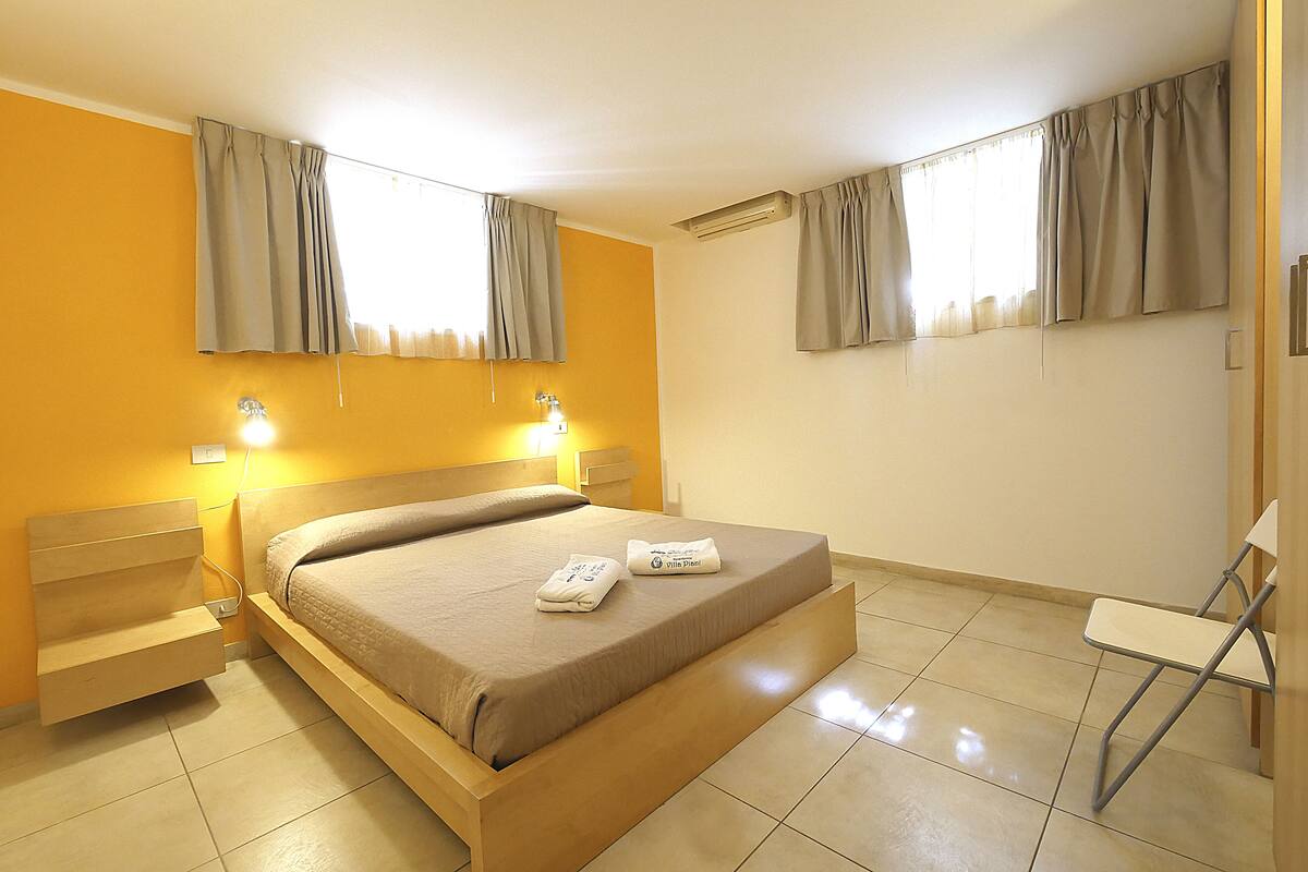 A hotel room with a bed, bedside tables, a chair, and curtains.