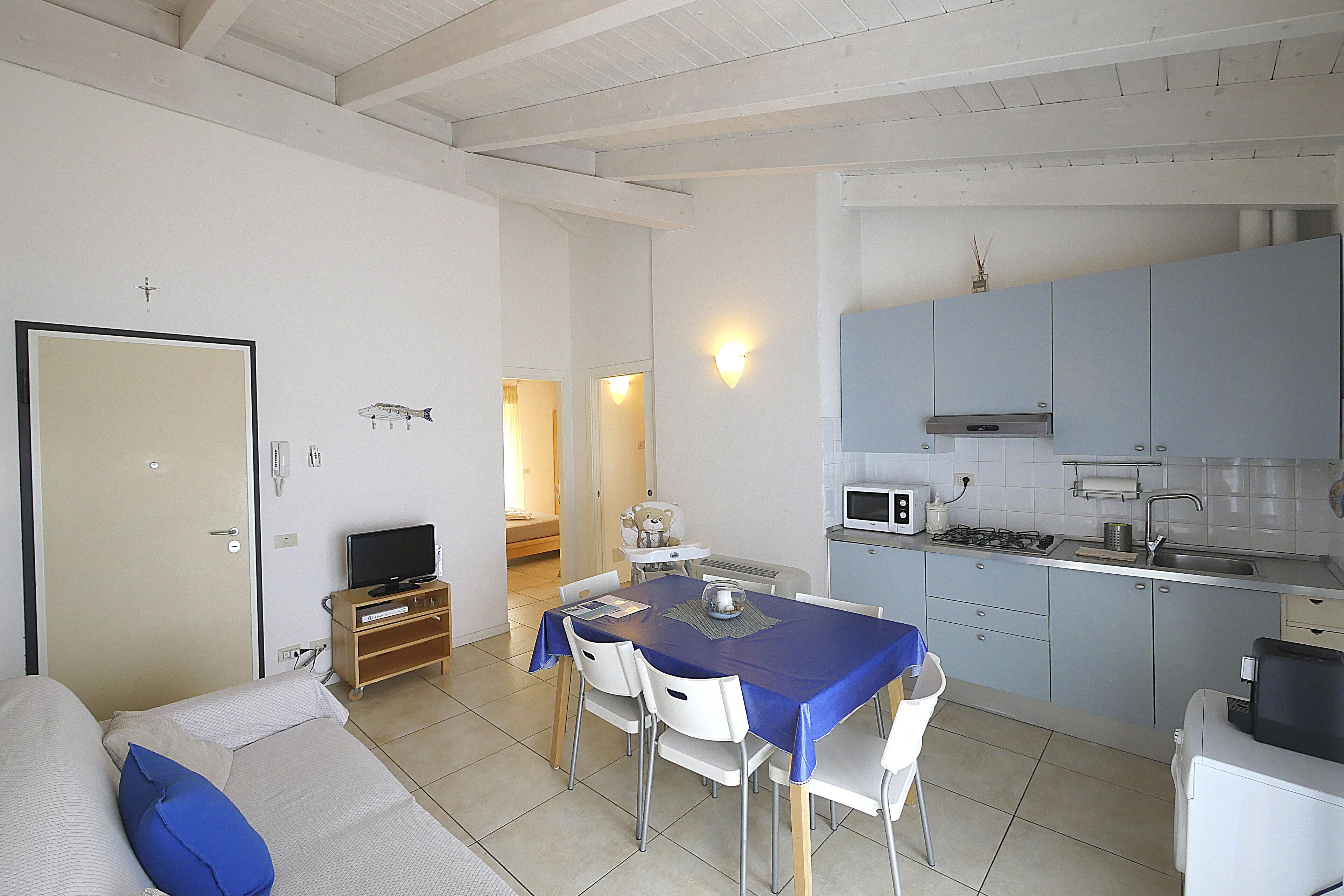 A compact living space with a dining area, kitchenette, and a bed with a blue pillow.