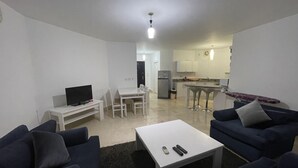 A modern living room with a TV, seating, and a kitchen in the background. - One bedroom (403) touristic area, near to Mamsha Street (Hurghada)