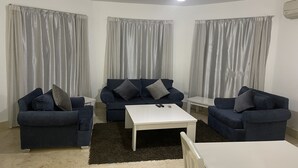 A living room with two dark blue sofas, a white coffee table, and grey curtains. - One bedroom (403) touristic area, near to Mamsha Street (Hurghada)