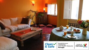 Una sala de estar con sofá, mesa de centro y comedor con mesa dispuesta para el desayuno.