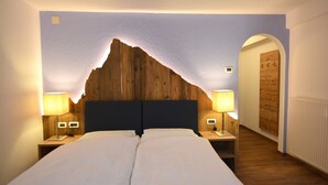 Une chambre à coucher avec une tête de lit en bois, deux tables de chevet avec des lampes et un couvre-lit blanc.