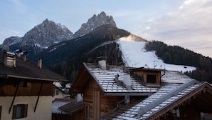 Un chalet de montagne avec un toit en pente, une façade en bois et une vue sur des montagnes enneigées.