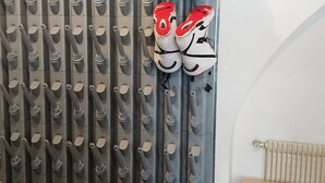 Un mur muni de plusieurs crochets pour suspendre des chaussures, un radiateur et un banc.