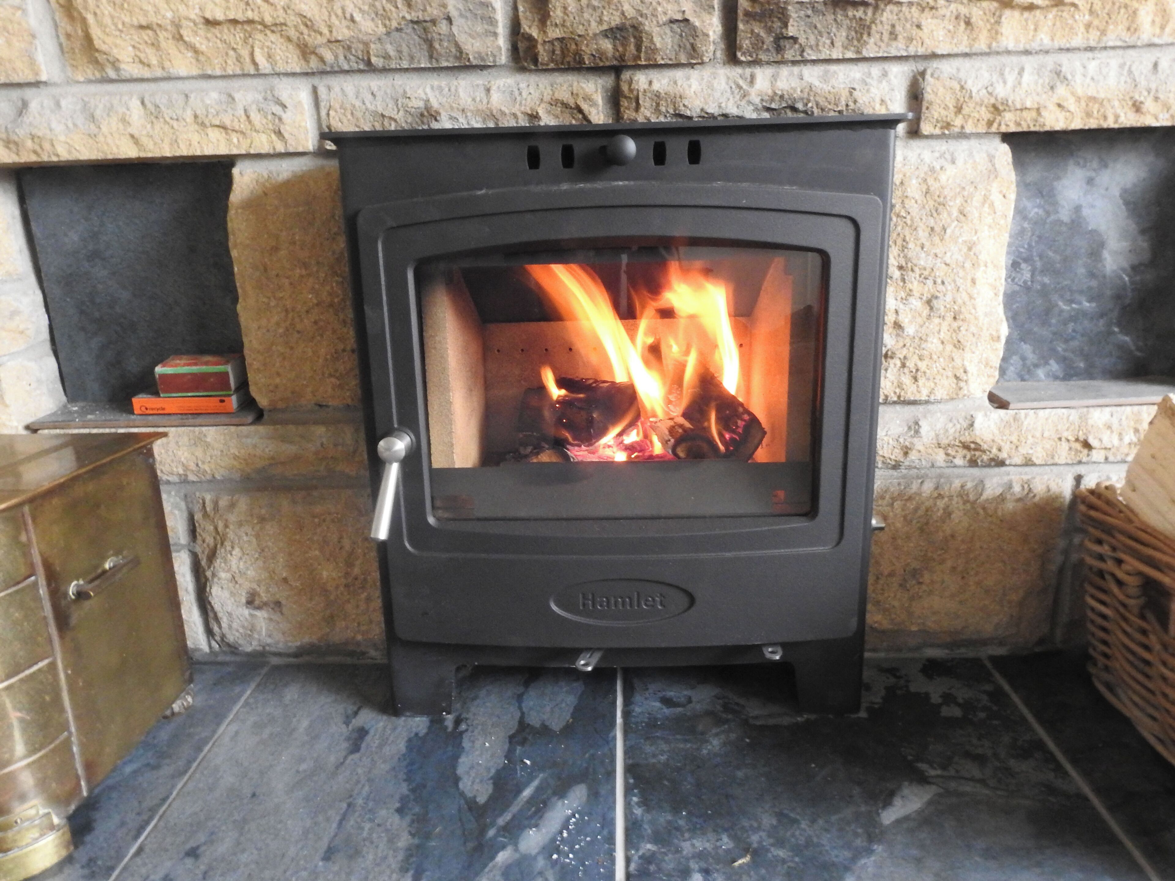 A wood-burning stove with a visible fire, set in a stone fireplace.