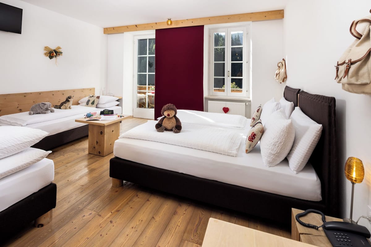 Habitación de hotel con dos camas, suelo de madera, un ventanal grande y vistas al exterior.