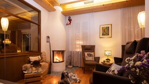 A cozy living room with a fireplace, wooden furniture, and a dog lying on the floor. - Small & Lovely Hotel Zaluna (Predazzo)