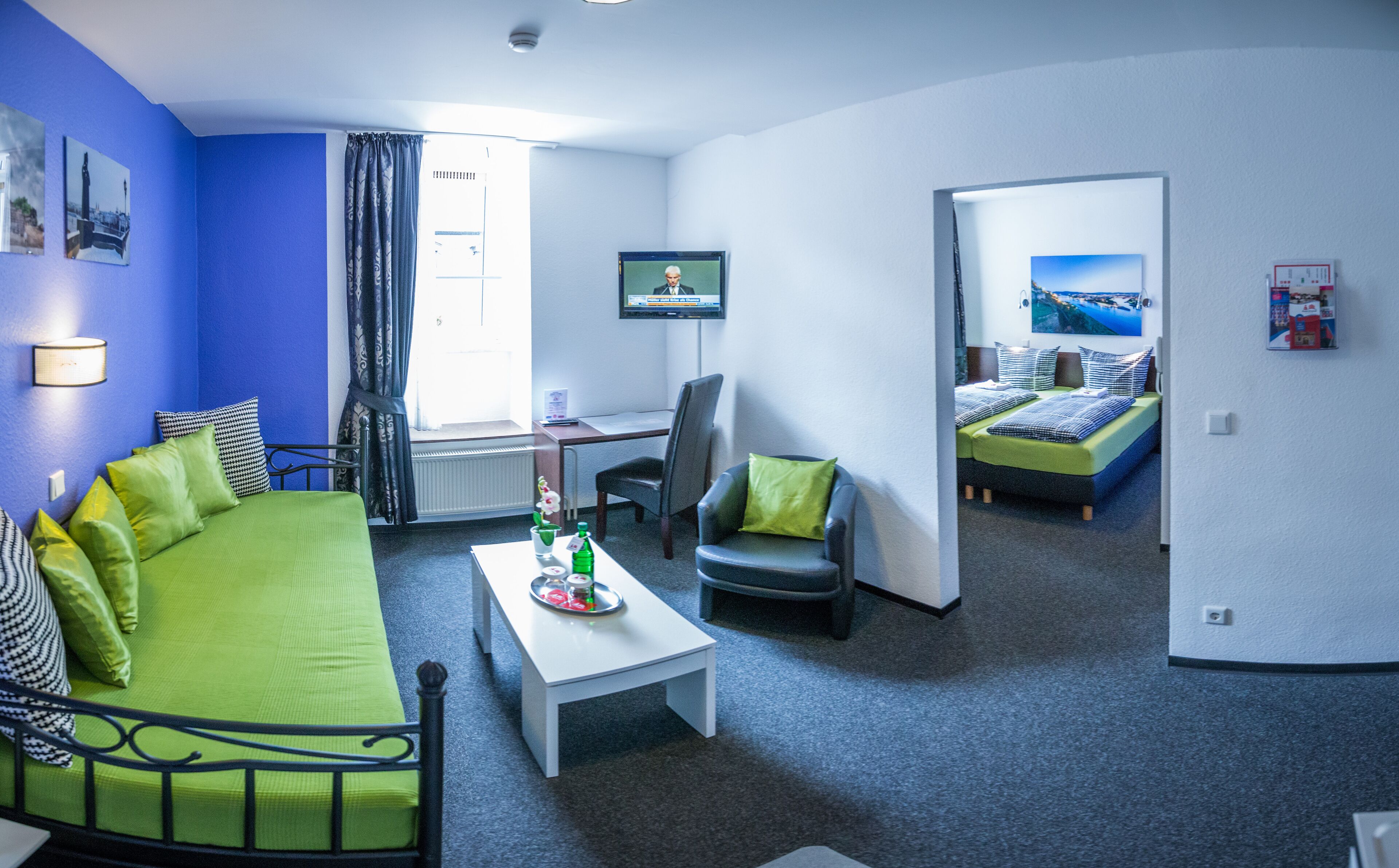 Una habitación de hotel con cama, escritorio, silla y televisor.