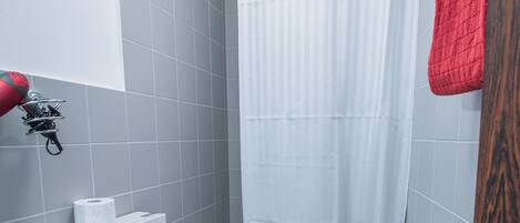 A bathroom with a white toilet, a shower curtain, and a red towel hanging on the wall.