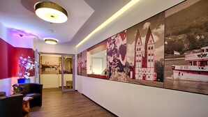En hall med en stor väggmålning, ett receptionsområde med ett skrivbord och stolar samt ett trägolv.