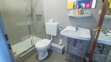 Une salle de bain avec une douche à parois de verre, des toilettes, un lavabo et un miroir.