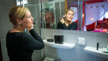 A bathroom with a mirror, a sink, and a shelf with toiletries.