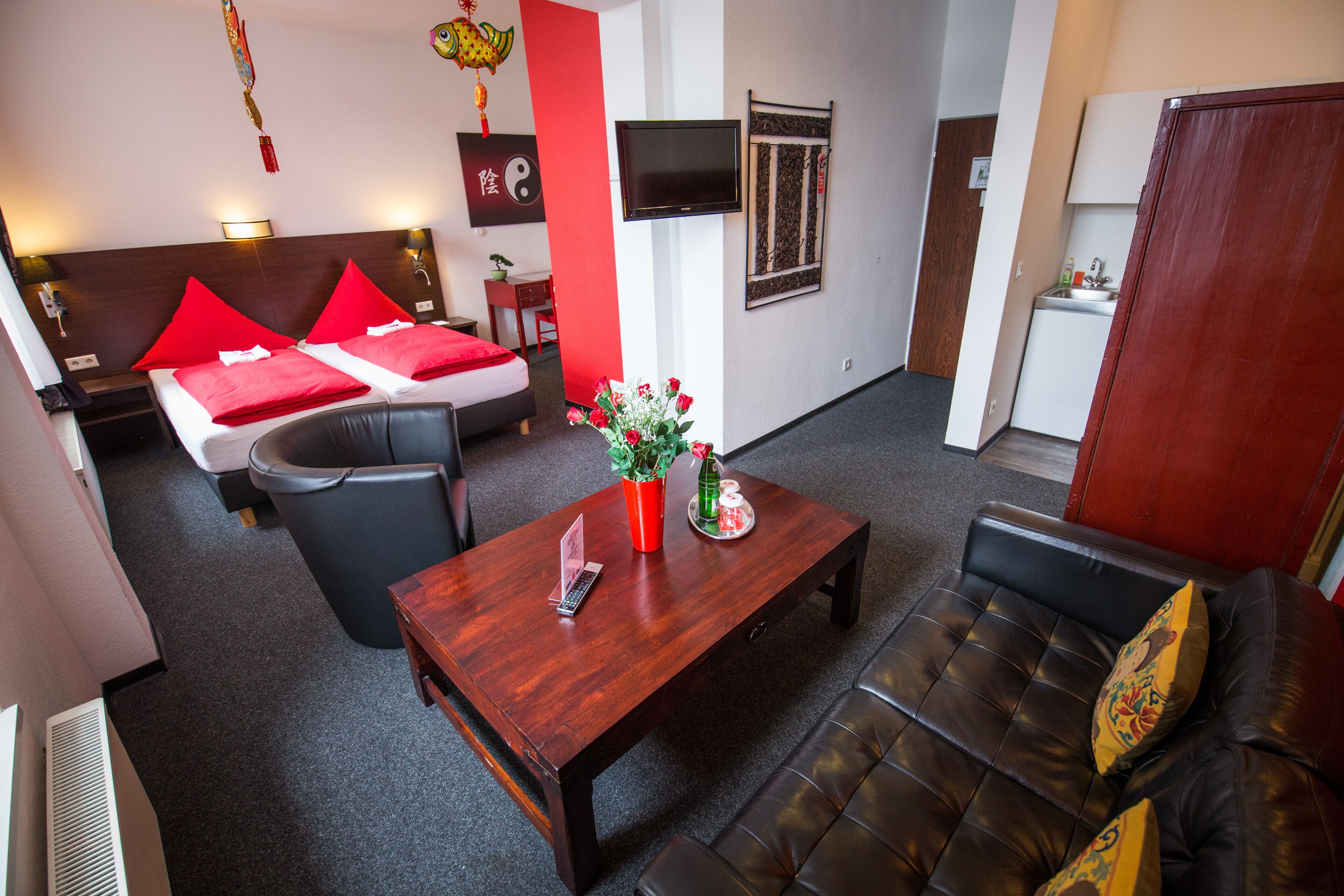 Een moderne hotelkamer met een bed, een bank, een salontafel en een televisie.