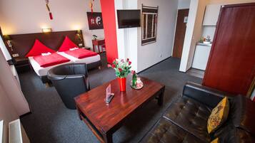Een moderne hotelkamer met een bed, een bank, een salontafel en een televisie.