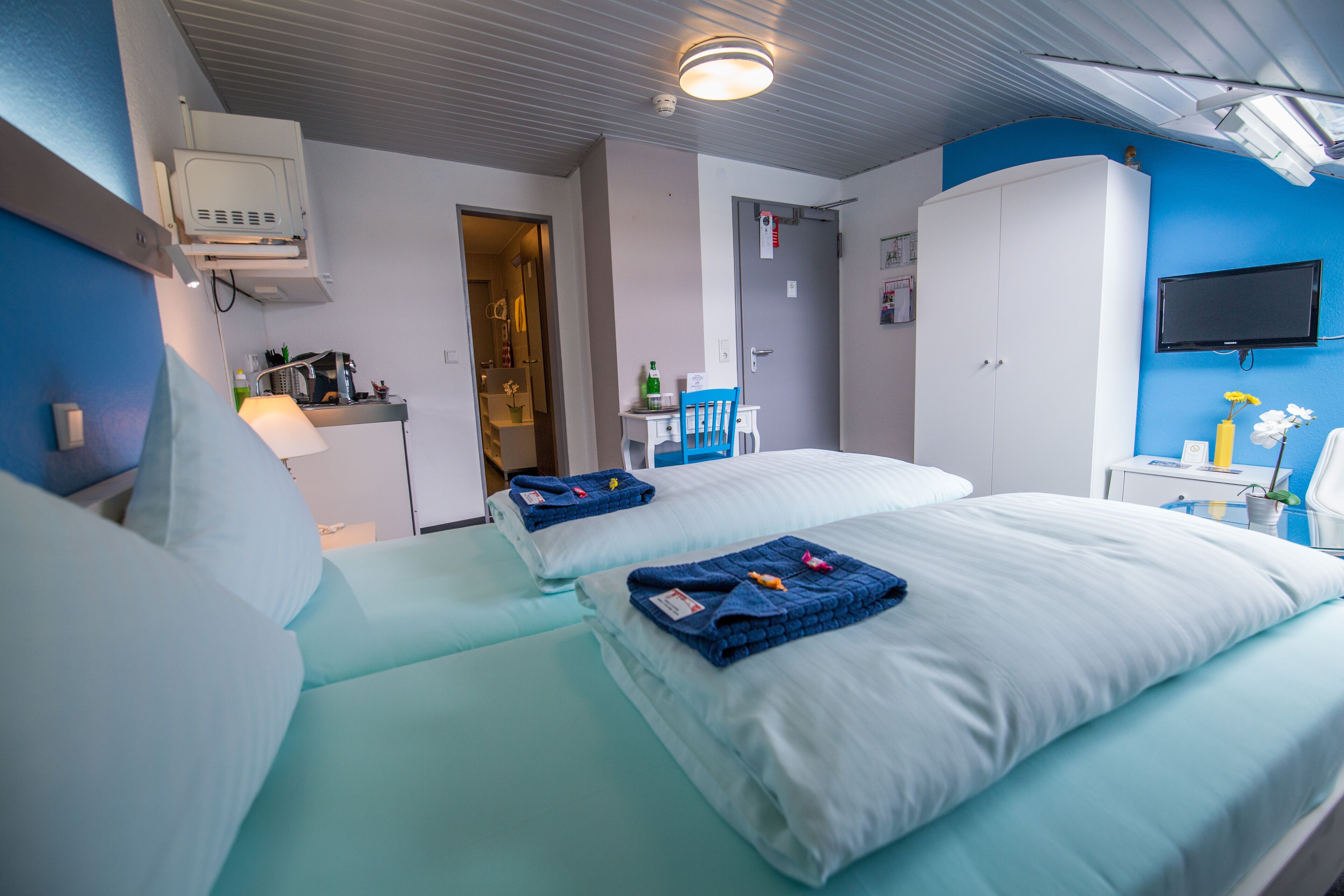 Une chambre d’hôtel avec deux lits, un bureau, une télévision et une armoire.