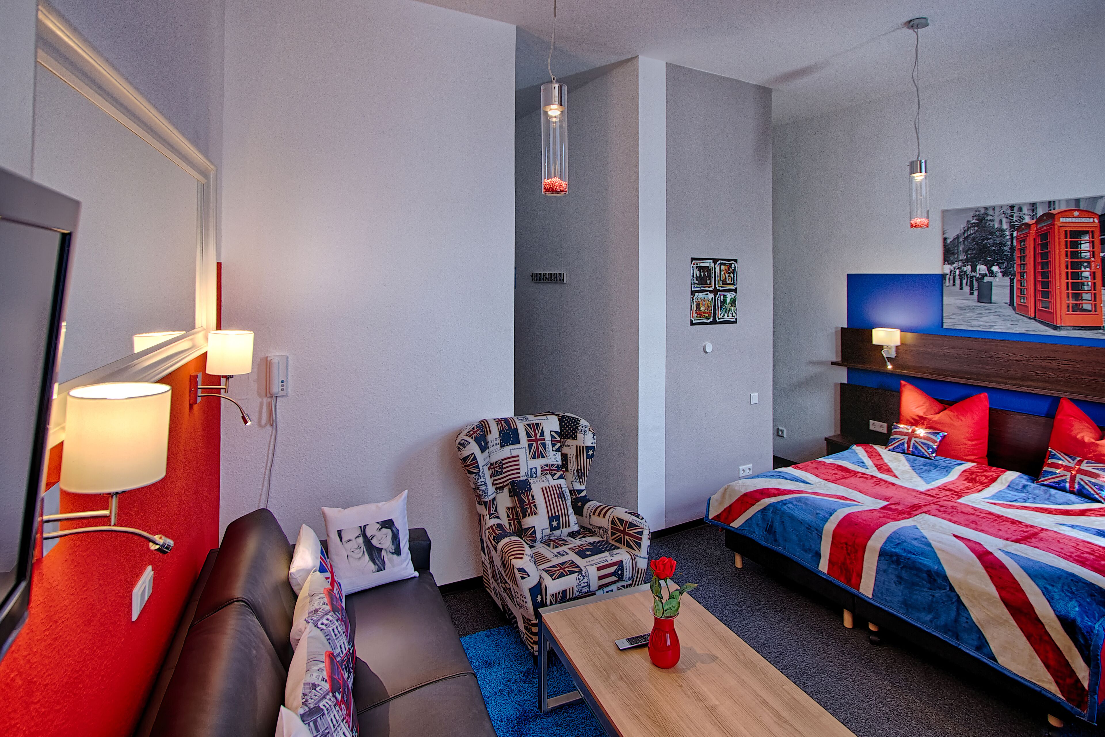 A hotel room with a bed, a sofa, a chair, a table, and a lamp.