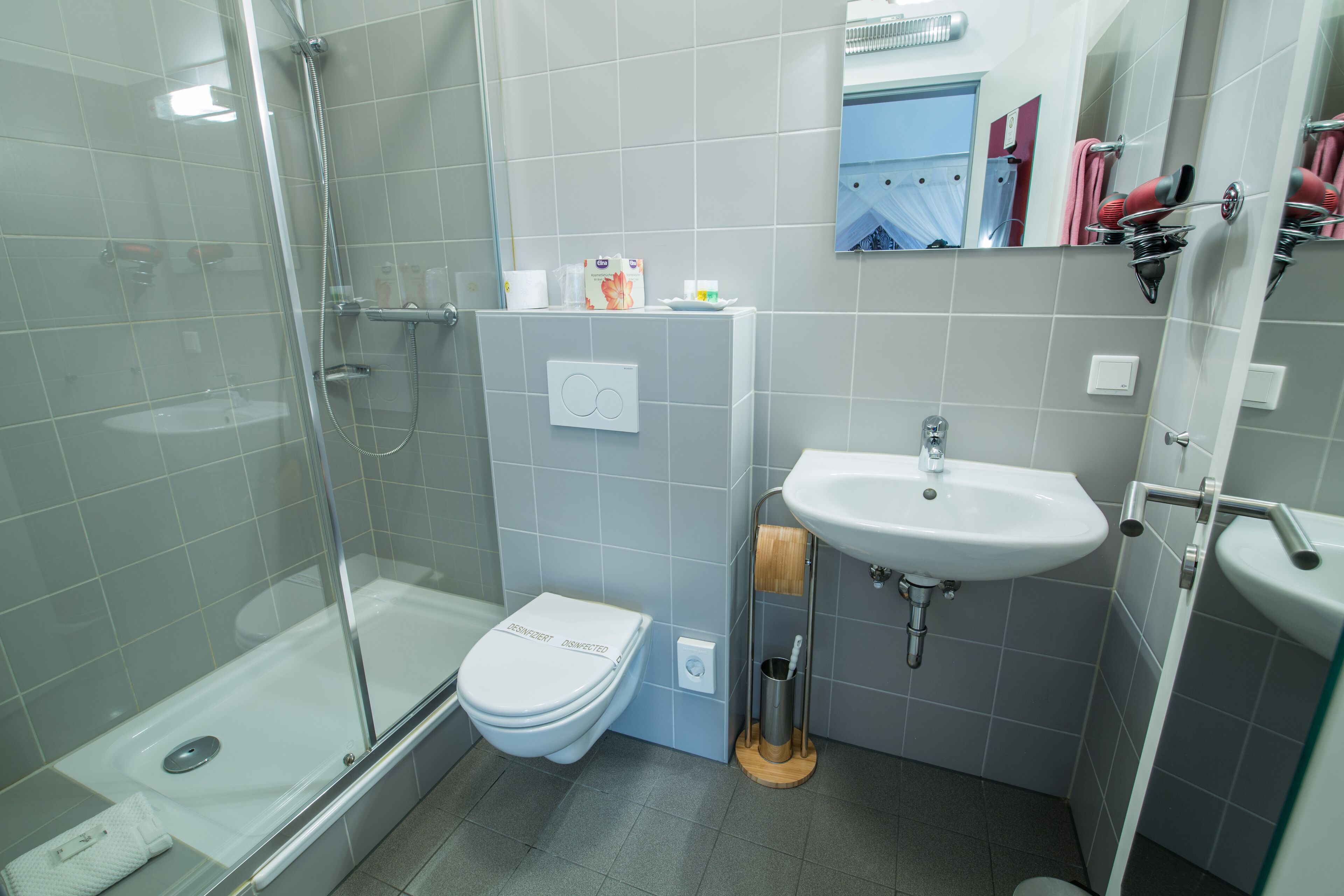 A modern bathroom with a glass-enclosed shower, a white toilet, and a sink with a mirror above it.