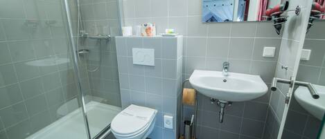 Un bagno moderno con doccia vetrata, un water bianco e un lavandino con uno specchio sopra.