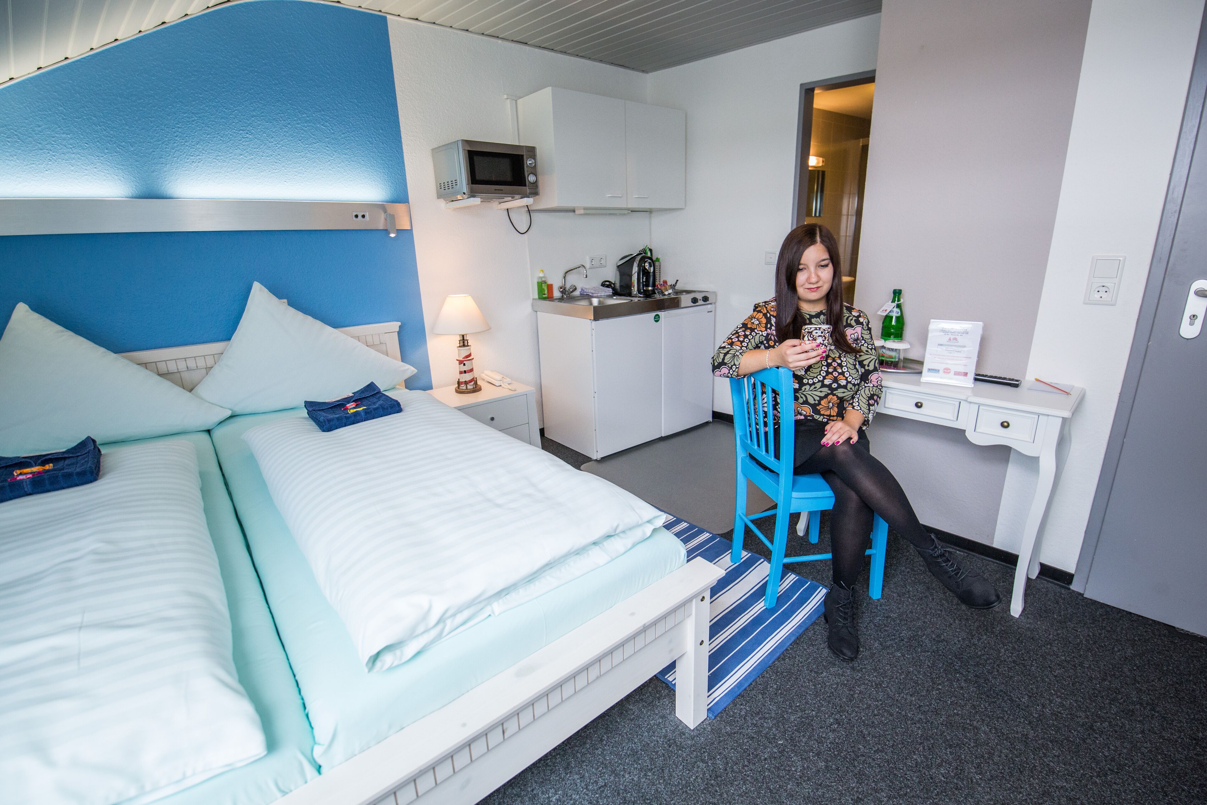 Una habitación de hotel con cama, escritorio, microondas y kitchenette.