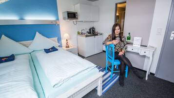 Una habitación de hotel con cama, escritorio, microondas y kitchenette.
