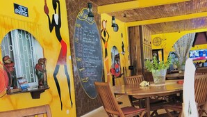 A restaurant with wooden furniture, a chalkboard menu, and a Coca-Cola sign. - Ifaty Beach Club (Ifaty)