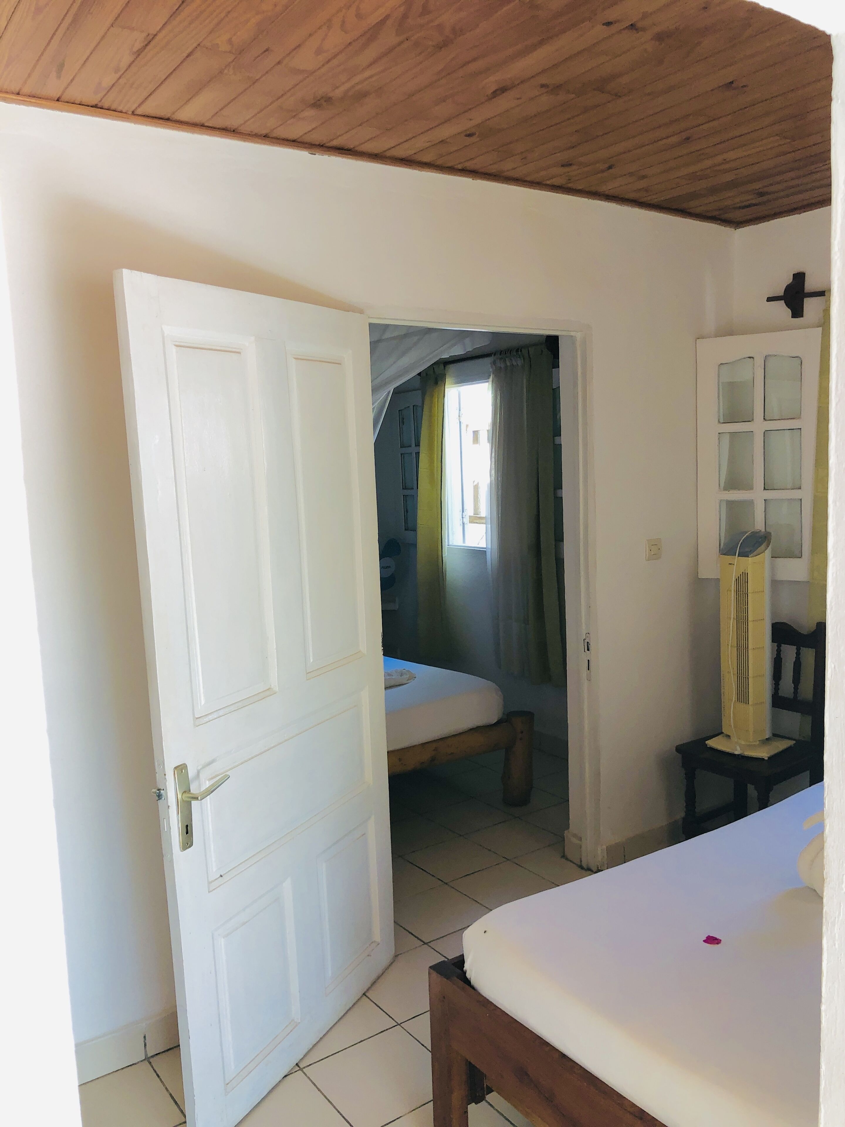 A room with a bed, a chair, a cabinet, and a door leading to another room.
