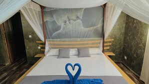 A bed with a canopy, a heart-shaped towel arrangement, and a mural on the wall. - Ifaty Beach Club (Ifaty)