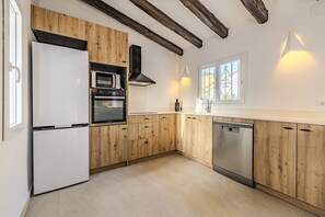A modern kitchen with wooden cabinetry, a built-in oven, a dishwasher, and a window providing natural light.