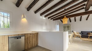 Una cucina moderna con mobili in legno, lavastoviglie e un'area pranzo con divano e sedie.