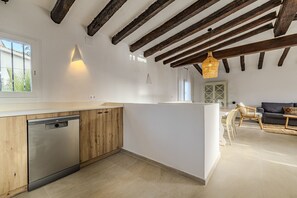 Une cuisine moderne avec des meubles en bois, un lave-vaisselle et un coin repas comprenant un canapé et des chaises.