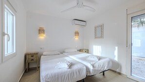 Una camera da letto con un letto, comodini, un condizionatore d'aria, luci a parete e una ventola a soffitto.