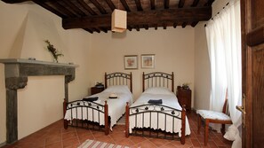 Una camera da letto con due letti, un soffitto in legno, un camino e una poltrona.