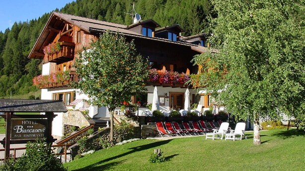 Um hotel com bar e restaurante, rodeado por uma área gramada e árvores.