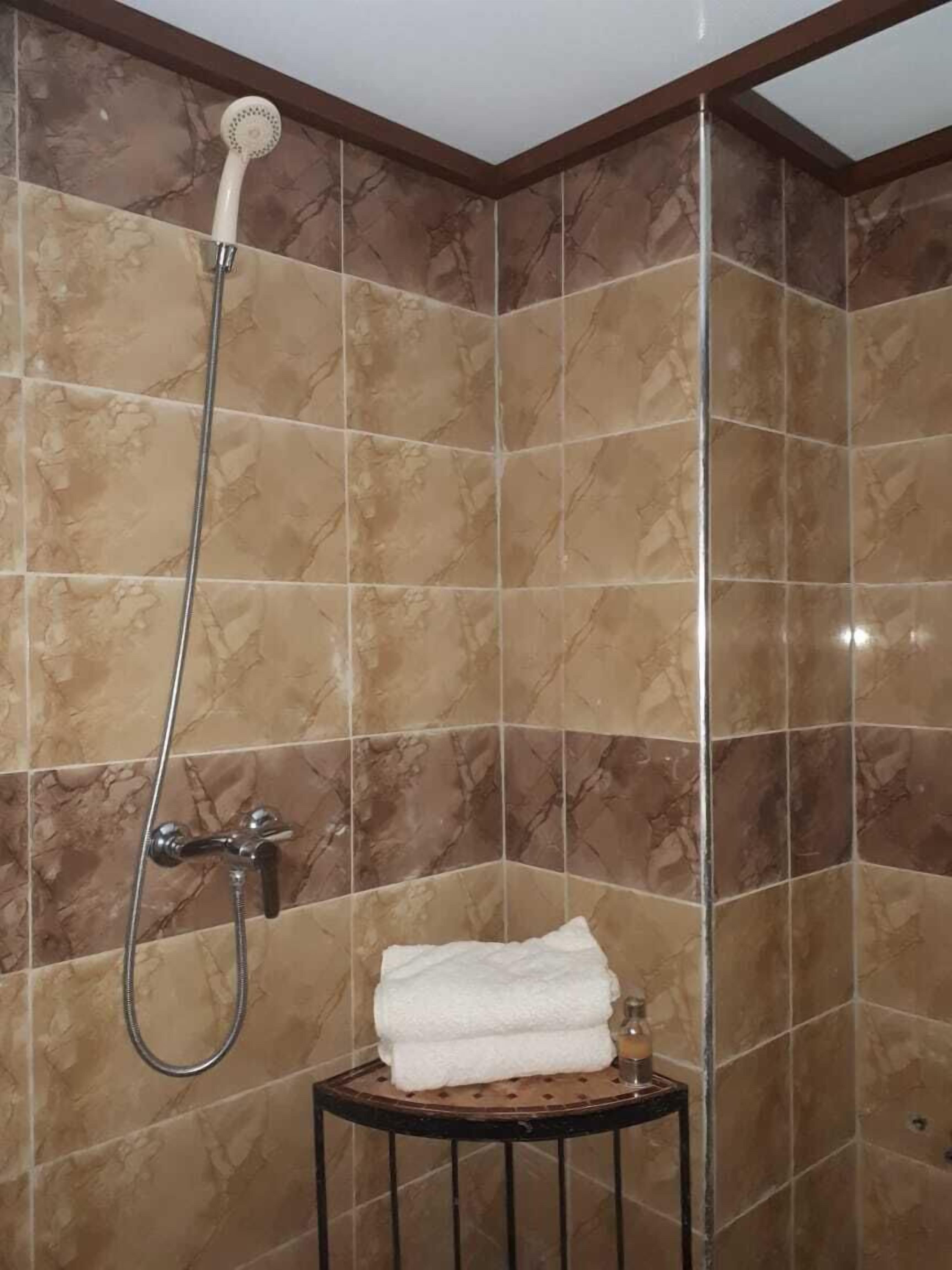 A shower area with a handheld showerhead and a wall-mounted faucet.