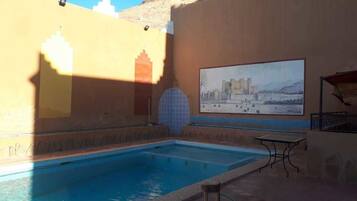 Una piscina al aire libre, sombrillas, sillones reclinables de piscina