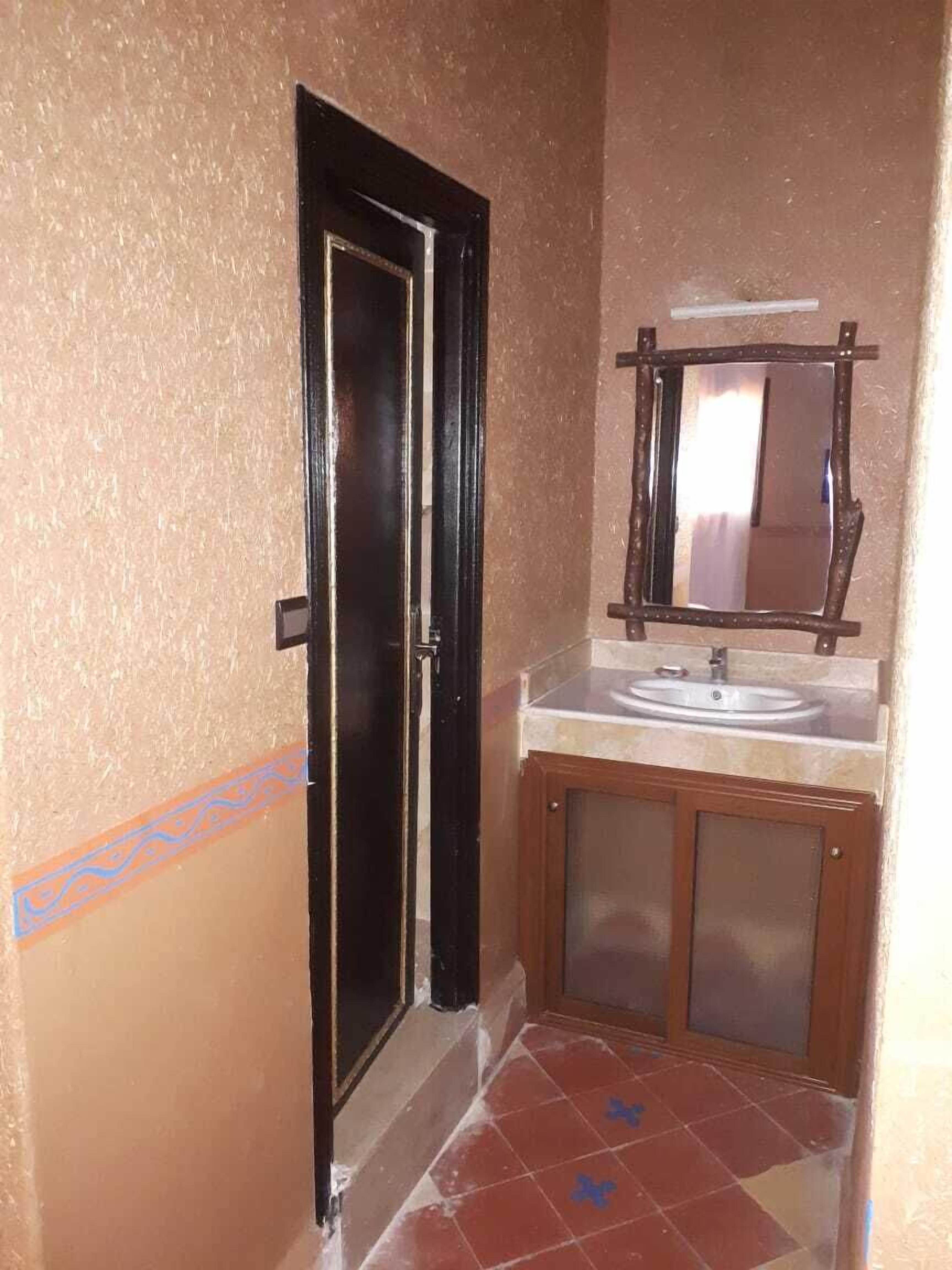 Un baño con lavamanos, espejo y puerta.