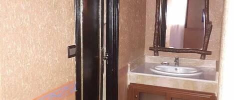 Un baño con lavamanos, espejo y puerta.
