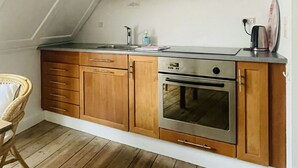 Een keuken met houten kastjes, een roestvrijstalen oven en een ingebouwde magnetron.