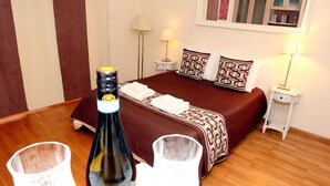 Une chambre d’hôtel avec un lit, des tables de chevet, des lampes et une bouteille posée sur une table.