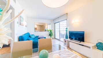 Ein modernes Wohnzimmer mit einer Couch, einem Fernseher und einem Glastisch.