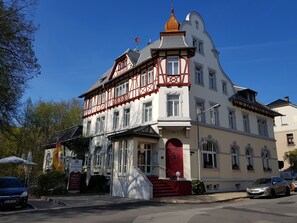 Un edificio histórico con una fachada prominente de rojo y blanco, múltiples ventanas y una escalera que conduce a la entrada.