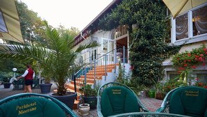 A courtyard with outdoor seating, a staircase, and a building with a balcony. - Parkhotel Meerane (Meerane)