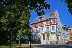 Un edificio histórico con una fachada llamativa en rojo y blanco, ventanas amplias y una torre prominente en la esquina.