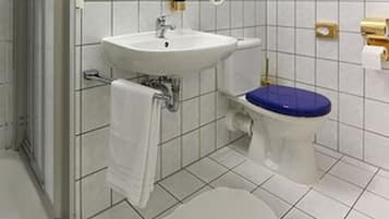 A bathroom with a glass shower enclosure, a white sink, a toilet with a blue seat, and a mirror above the sink.