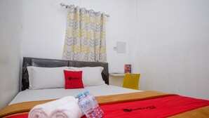 A hotel room with a bed, a red and white pillow, a water bottle, and a red blanket. - RedDoorz near Politeknik Manado (Manado)