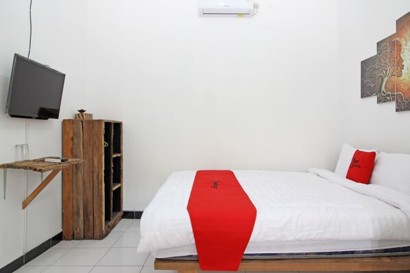 Ein Hotelzimmer mit einem Bett, einem an der Wand montierten Fernseher und einem Holzschrank.