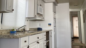 A kitchen with white cabinetry, a granite countertop, and a microwave. - Houseboat offers a rooftop deck for stunning views of the sunrise and sunset. (Tavernier)