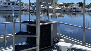 A marina with boats docked, a covered area with a table and benches, and a view of the marina in the background. - Houseboat offers a rooftop deck for stunning views of the sunrise and sunset. (Tavernier)